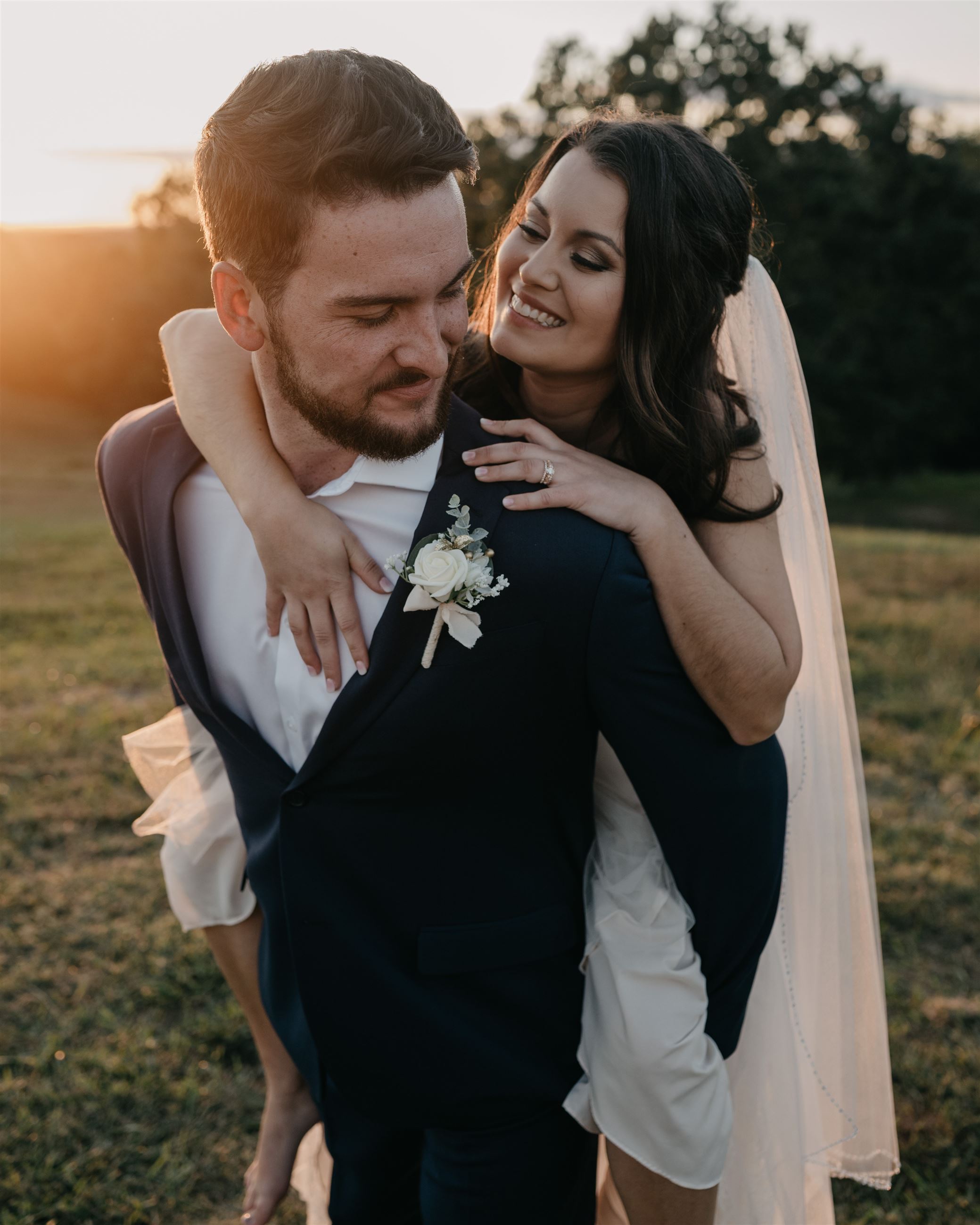 Bride on grooms back as they smile at each other